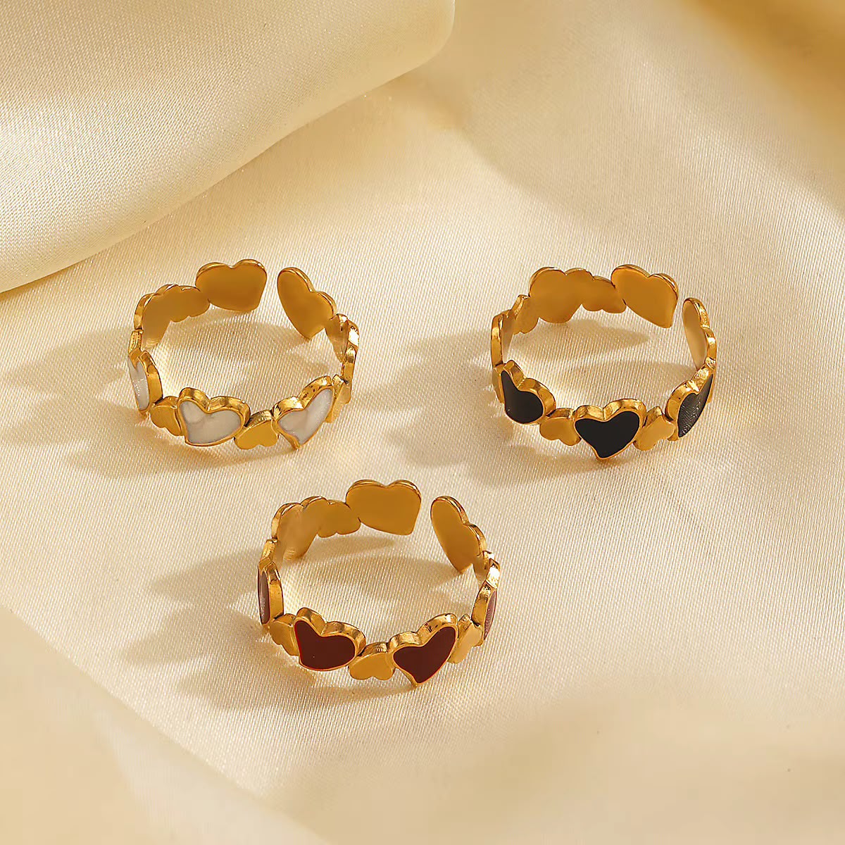 Set of 3 gold heart rings with white, red and black enamel hearts on cream silk